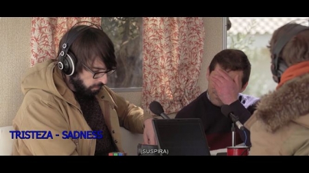 Fotograma del video subtitulado donde se observan las descripciones en blanco del sonido de la persona y en azul su emoción (UGR) 