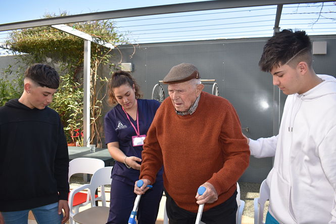 Dos estudiantes acompañando a un anciano (AYTO. CHURRIANA)
