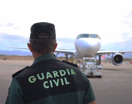 Un agente de la Guardia Civil, de espaldas, en la pista de un aeropuerto con un avión al fondo (GUARDIA CIVIL)