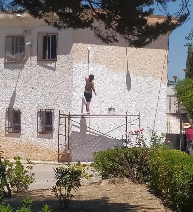 Una mujer blanquea una fachada afectada por la calima en Montefrío (AYTO. MONTEFRIO)