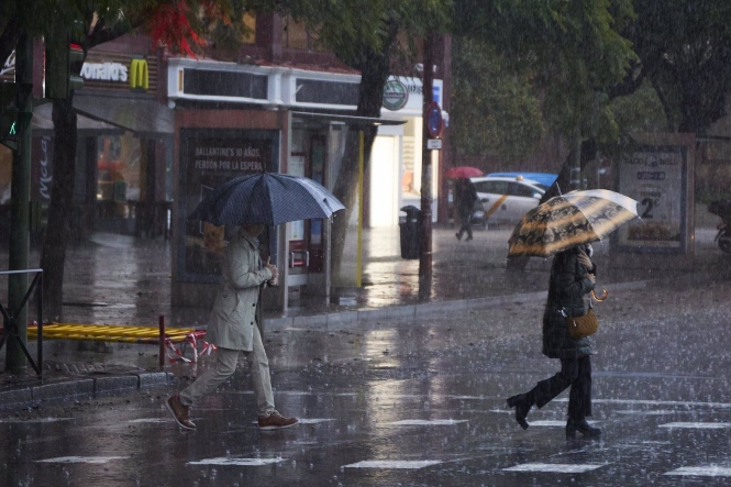 Dos mujeres se refugian de la lluvia en sus paraguas (JOAQUÍN CORCHERO / EUROPA PRESS)