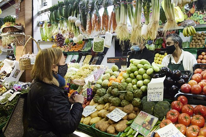 Una señora realiza un pedido en un puesto de frutas y verduras (JOAQUÍN CORCHERO / EUROPA PRESS)