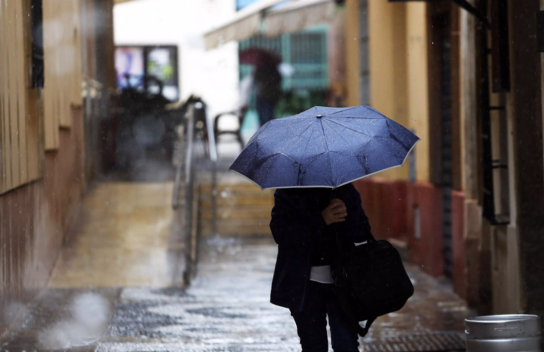 Una persona se protege de la lluvia en Málaga. Imagen de archivo (ÁLEX ZEA / EUROPA PRESS
