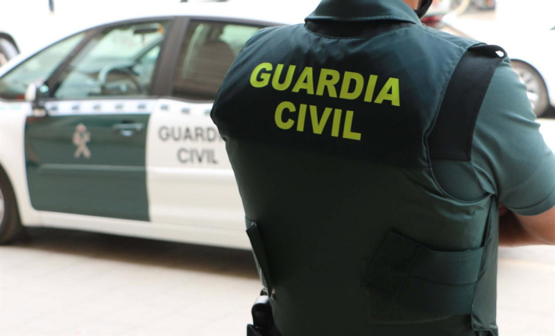 Agente de la Guardia Civil junto an vehículo del instituto armado (GUARDIA CIVIL) Agente de la Guardia Civil junto an vehículo del instituto armado (GUARDIA CIVIL)