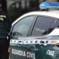 Un agente de la Guardia Civil, de espaldas, de pie junto a un vehículo oficial (GUARDIA CIVIL)